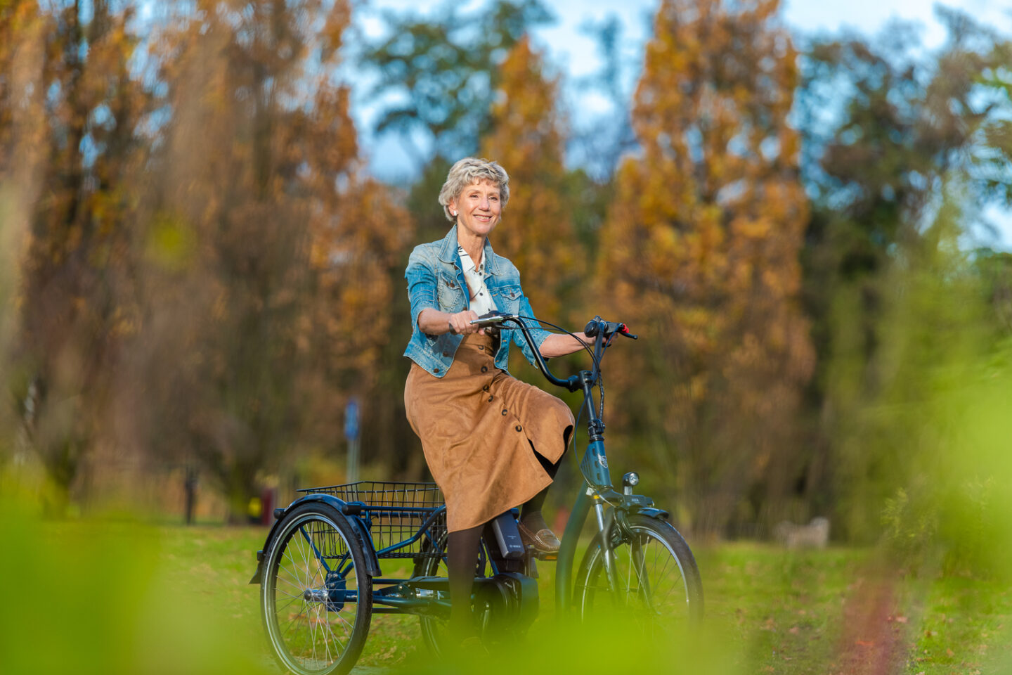 oude vrouw fiets door park met een driewielfiets